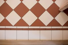 an empty bench in front of a wall with brown and white tiles on it's sides