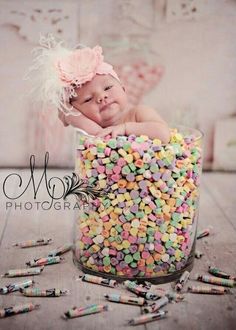 a baby is laying in a jar full of candy