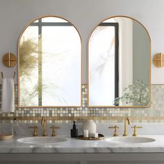 three oval mirrors are above two sinks in a bathroom with marble counter tops and gold faucets