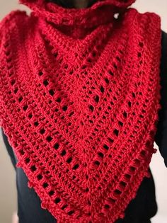 a woman wearing a red crocheted shawl on top of a black shirt