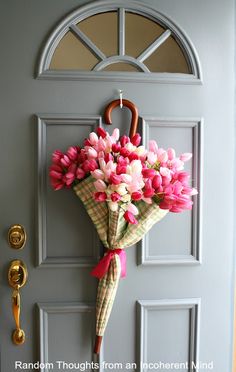 a bouquet of flowers is hanging on the front door with an umbrella attached to it