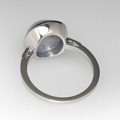 This lovely ring is centered with one (1) round cabochon cut natural star sapphire set into a bezel setting. The shoulders of the ring are each accented with two (2), bead set, round brilliant cut diamonds, bordered with milgrain edging. The ring measures 13.5mm at the top, rises 8.8mm above the finger, tapering to 1.4mm wide and 1.5mm thick at the base of the shank. It is currently a size 7.5. This gorgeous star sapphire has a natural inclusion near the edge but this is very difficult to see wh Formal Polished Finish Oval Cabochon Sapphire Ring, Modern Sapphire Ring Oval Cabochon Polished Finish, Oval Cabochon Opal Ring With Polished Finish, Modern Sapphire Ring With Oval Cabochon And Polished Finish, Formal Domed Cabochon Sapphire Ring, Bezel Set Diamond Gemstones, Classic Oval Cabochon Sapphire Ring With Bezel Setting, Classic Sapphire Ring With Oval Cabochon Bezel Setting, Round Diamond Gemstones With Bezel Setting