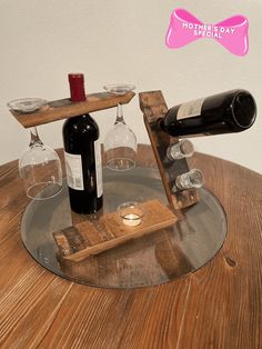 two wine glasses are sitting on top of a wooden table with some wine bottles in it