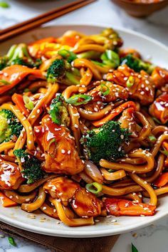 a white plate topped with chicken and broccoli covered in sesame seed sauce next to chopsticks