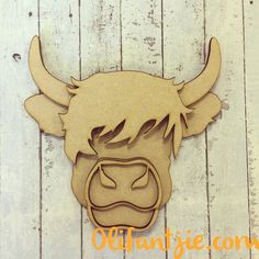 a wooden cutout of a cow's head on a white wood plank background