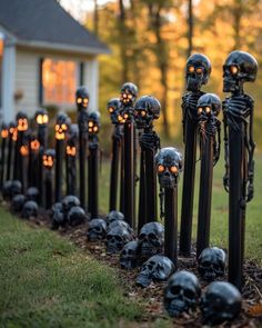 a row of halloween skeleton heads in front of a house with pumpkins on them