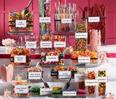 a table topped with lots of different types of candies and candy bar signs next to each other