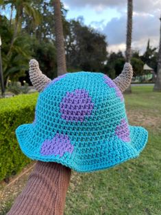 a person wearing a crocheted blue and purple hat with horns on their head