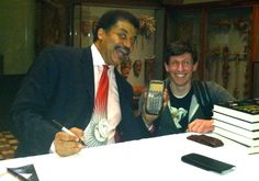 two men sitting at a table with some books and cell phones in front of them