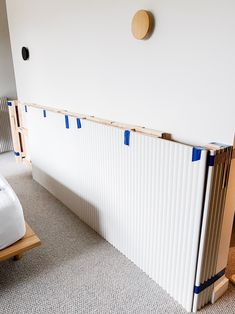 a bed sitting next to a white wall with blue tape on it's sides