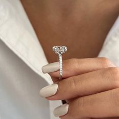 a woman's hand holding a ring with a heart shaped diamond on the side