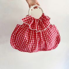 Vintage Red Gingham Cotton Bag. This charming piece features a ruffled top with decorative buttons, circular metallic handles, and a spacious interior. Made from a cotton fabric, it showcases a classic red and white vichy pattern. CONDITIONS Excellent Conditions DESCRIPTION No brand tag Material: Cotton (no composition label inside) Color: Red, White MEASUREMENTS  Height 36 cm (14") Length 52 cm (20.4") Drop 12 cm (4.7") measurements are taken seam to seam with the item laid flat (I suggest comp Spring Picnic Cotton Bag, Cotton Summer Picnic Bag, Summer Cotton Bag For Picnic, Cotton Picnic Bag For Summer, Red Cotton Bag For Summer, Chic Ruffled Shoulder Bag For Spring, Summer Cotton Gingham Bags, Summer Gingham Cotton Bags, Gingham Cotton Bags For Summer