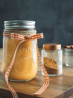 a jar filled with food sitting on top of a wooden table next to two jars