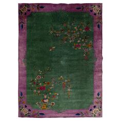 a green rug with purple border and flowers on the bottom, in front of a white background