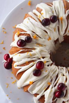 a white plate topped with a cake covered in icing and cranberries