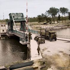 an old black and white photo of men working on a bridge over a river with trucks