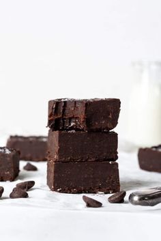 three pieces of chocolate brownie stacked on top of each other with milk in the background