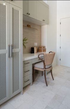 a chair sitting in front of a desk with a cabinet and cupboards behind it