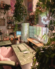 a desk with two computer monitors, keyboard and mouse on it in front of some potted plants