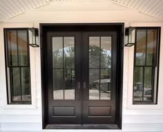 a black double door with two sidelights on the front of a white house,