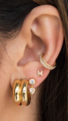 a close up of a person's ear with three different types of earrings on it