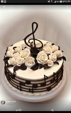 a cake decorated with music notes and white roses