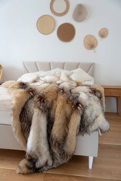 a bed covered in fur sitting on top of a wooden floor next to a wall