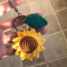 a hand holding a crocheted keychain with a sunflower on it