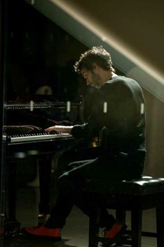 a man sitting at a piano in the dark