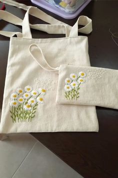 two white bags with daisies embroidered on them