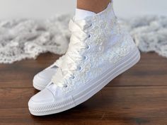 Consider these lacey sneakers like your favorite Converse, but personalized specifically for your wedding day. Forget traditional shoelaces; these white sneakers are tied with a romantic ribbon. (Choose from one of 20 different colored ribbons.) You can also personalize the heel with your initials and wedding date and add pearls to the toe cover. Or, keep it simple with the lovely lace speaking for itself. - Upper piece of durable canvas fabric - Classic toe cover made of cast rubber sole - All White Wedding Converse, White Lace-up Sneakers, Low-top Lace Sneakers With Laces, Low-top Wedding Shoes With White Laces, White Lace-up Sneakers With Lace Material, Low-top Lace Wedding Shoes For Bride, White Lace Sneakers With Round Toe, White Lace Round Toe Sneakers, Lace-up Lace Wedding Shoes With Lace Trim