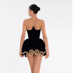 the back of a woman in a short black dress with gold sequins on it