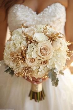 a bridal holding a bouquet of white and gold flowers