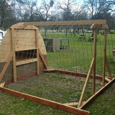 a chicken coop in the middle of a grassy area with wooden posts and fencing around it