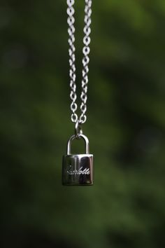 a close up of a padlock on a chain with trees in the back ground