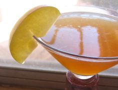 a close up of a drink in a glass with an apple slice on the rim