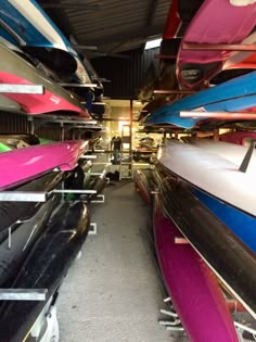 many different colored boats are lined up in a storage area with one boat upside down