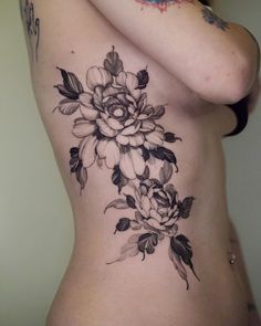 a woman's stomach with black and white flowers on her side, which is covered in tattoos