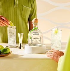 two people are sitting at a table with drinks and limes