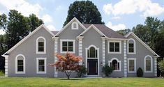 a large gray house sitting on top of a lush green field