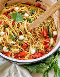 a pot full of pasta with tomatoes and basil