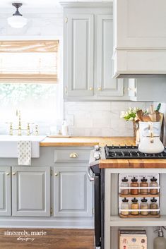 a kitchen with white cabinets and wooden counter tops