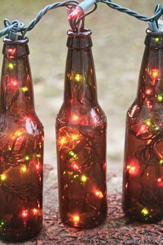 three brown glass bottles with christmas lights in them