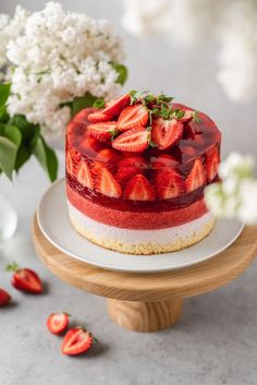 a cake with strawberries on top is sitting on a plate next to some flowers