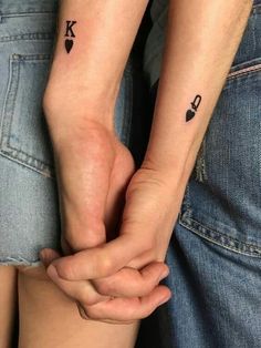 two people holding hands with tattoos on their arms