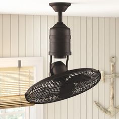 a ceiling fan hanging from the ceiling in a room with white walls and wood paneling