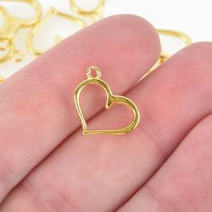 "Very versatile open heart charms in a shiny metal finish. These are a nice size for earrings or a charm on a necklace. Color: gold plated Size: 16mm x 13mm ( 5/8\" x 4/8\") Hole size: 1.5mm Thickness: 2mm Quantity: 50 charms \"Tested in-house no nickel detected.\"" Open Heart, Plate Size, A Necklace, Heart Charm, Wedding Favors, Heart Ring, 50 %, Gold Plate, Charms