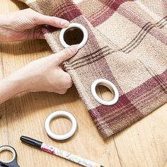 someone is holding onto some scissors to cut out the ring handles on a piece of fabric