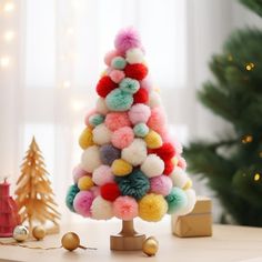 a christmas tree made out of pom - poms on a table next to a christmas tree