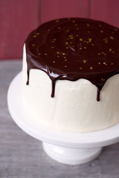 a cake with white frosting and chocolate drizzled on it's top